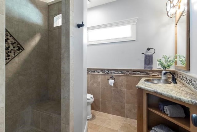 8127 Lone Elm Rd, Lenexa, KS 66220 - bathroom with vanity, toilet, a tile shower, tile walls, and tile patterned floors