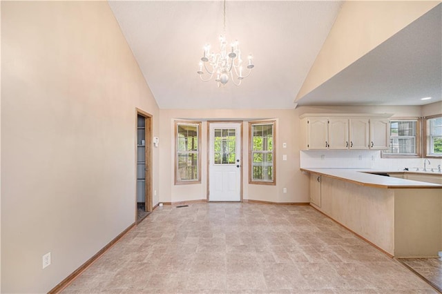 kitchen featuring a chandelier, a sink, light countertops, baseboards, and backsplash