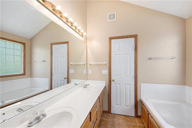 full bath featuring lofted ceiling, a bath, double vanity, and tile patterned floors