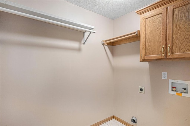 laundry room featuring electric dryer hookup, hookup for a washing machine, cabinet space, a textured ceiling, and baseboards
