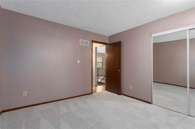 4010 Hedges Ave, Kansas City, MO 64133 - unfurnished bedroom with a closet, a textured ceiling, carpet flooring, and baseboards