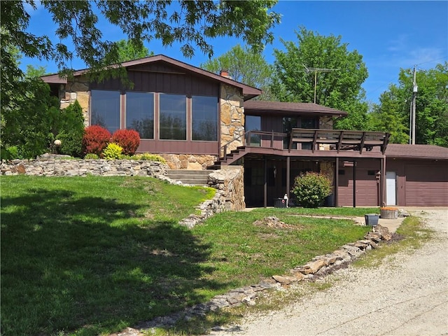 33295 Bethel Church Rd, Osawatomie, KS 66064 - view of front facade with stone siding, a wooden deck, a front lawn, and driveway