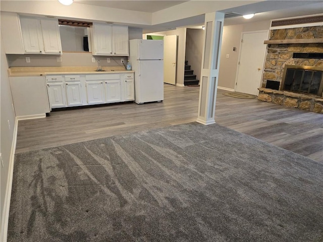 33295 Bethel Church Rd, Osawatomie, KS 66064 - kitchen featuring freestanding refrigerator, wood finished floors, baseboards, and white cabinetry