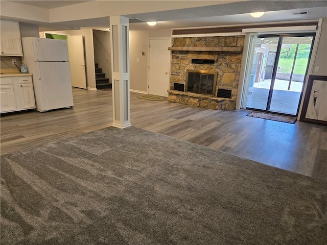 33295 Bethel Church Rd, Osawatomie, KS 66064 - unfurnished living room featuring wood finished floors, stairway, baseboards, and a stone fireplace