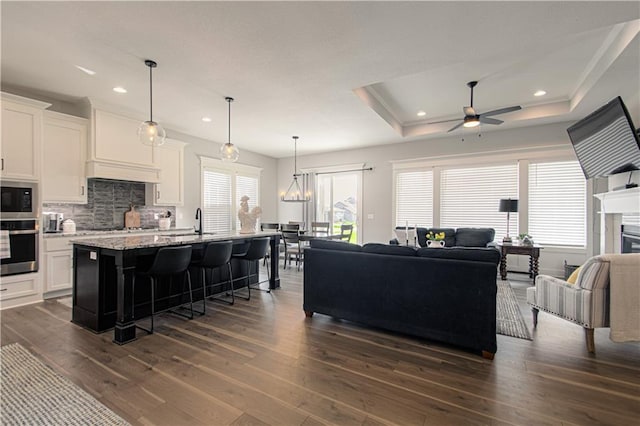 11410 Bluestem Dr, Kearney, MO 64060 - living room with dark wood-style floors, ceiling fan, recessed lighting, a raised ceiling, and a fireplace