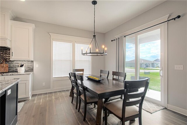 11410 Bluestem Dr, Kearney, MO 64060 - dining room featuring a chandelier, light wood-style flooring, baseboards, and healthy amount of natural light