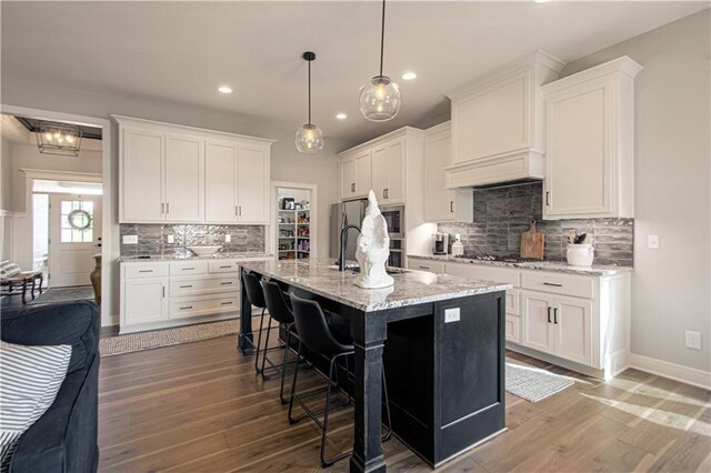 11410 Bluestem Dr, Kearney, MO 64060 - kitchen with decorative backsplash, stainless steel appliances, white cabinetry, a kitchen bar, and recessed lighting
