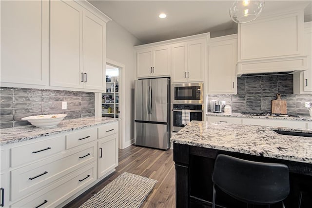 11410 Bluestem Dr, Kearney, MO 64060 - kitchen with appliances with stainless steel finishes, white cabinets, backsplash, wood finished floors, and light stone counters