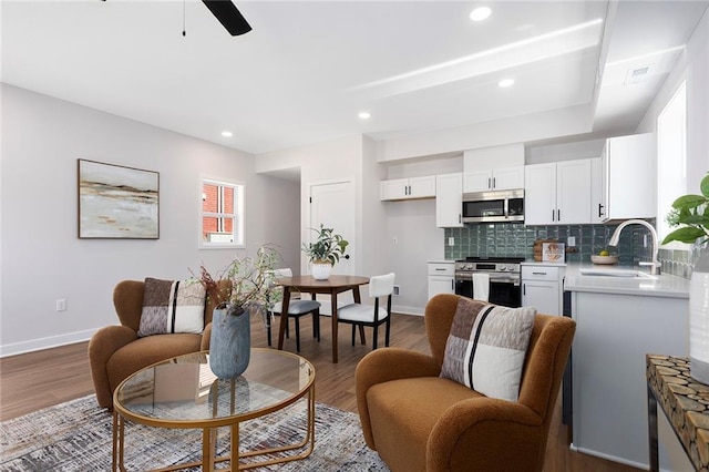 living room with baseboards, wood finished floors, ceiling fan, and recessed lighting