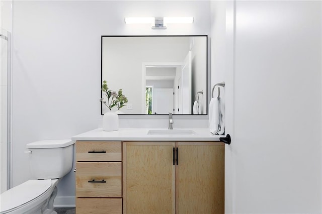 bathroom with toilet, vanity, and baseboards