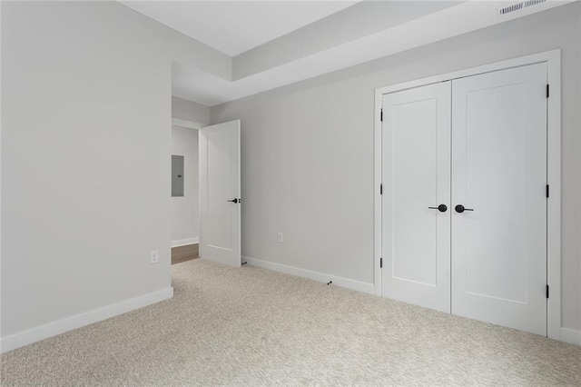 unfurnished bedroom with carpet, electric panel, baseboards, and a closet