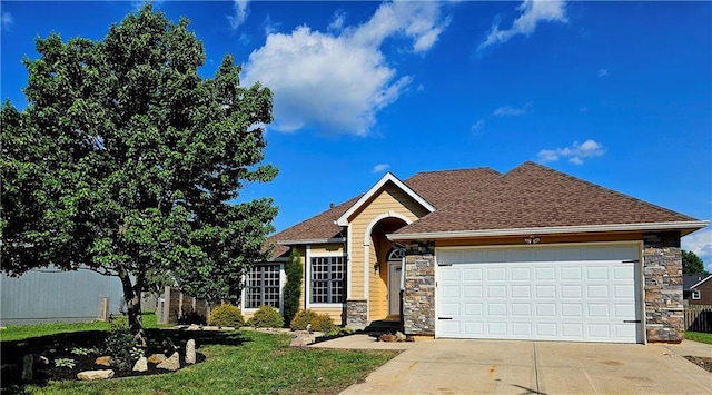 1309 Thomas Dr, Louisburg, KS 66053 - view of front of house featuring stone siding, driveway, a garage, and a shingled roof