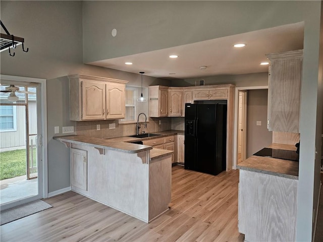 1309 Thomas Dr, Louisburg, KS 66053 - kitchen featuring black fridge with ice dispenser, a sink, a peninsula, light wood finished floors, and recessed lighting