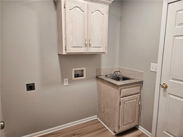 1309 Thomas Dr, Louisburg, KS 66053 - laundry room with electric dryer hookup, hookup for a washing machine, cabinet space, light wood finished floors, and baseboards