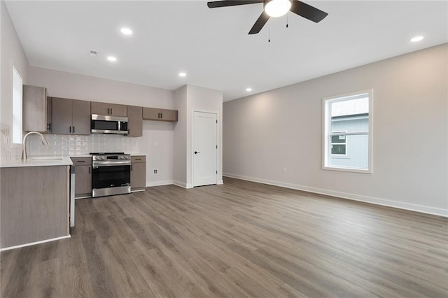kitchen with stainless steel appliances, a sink, light countertops, wood finished floors, and a ceiling fan