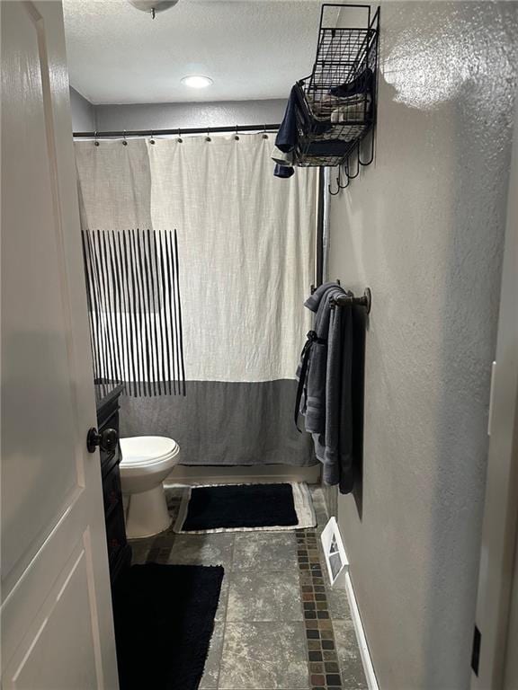 full bathroom featuring baseboards, toilet, a textured ceiling, a shower with shower curtain, and a textured wall
