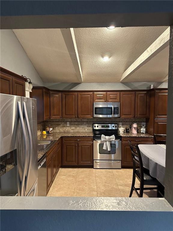 kitchen with stainless steel appliances, decorative backsplash, light tile patterned floors, and a textured ceiling