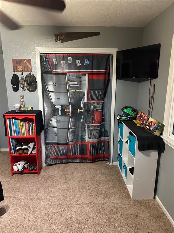 rec room featuring carpet floors, a textured ceiling, and baseboards