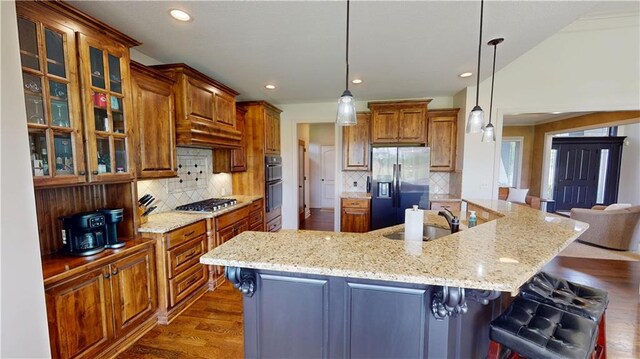 4301 N 141st St, Basehor, KS 66007 - kitchen with appliances with stainless steel finishes, a sink, a large island with sink, brown cabinets, and recessed lighting