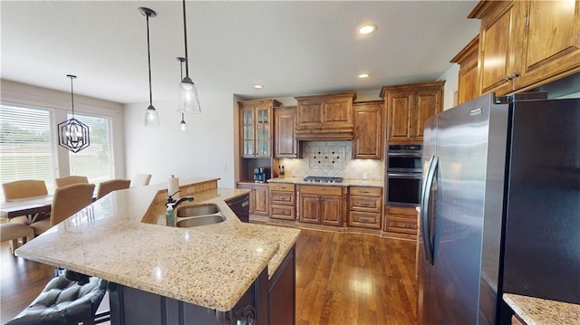 4301 N 141st St, Basehor, KS 66007 - kitchen with appliances with stainless steel finishes, a sink, brown cabinetry, dark wood-type flooring, and a kitchen bar