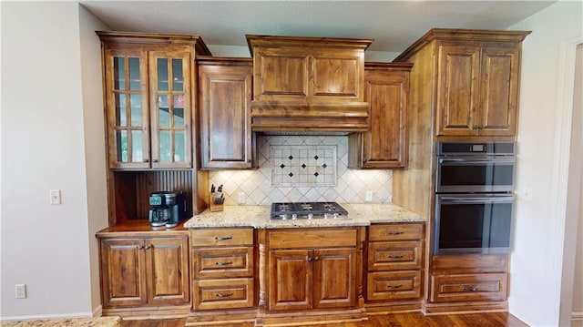 4301 N 141st St, Basehor, KS 66007 - kitchen with stainless steel appliances, backsplash, glass insert cabinets, light stone counters, and dark wood-style flooring