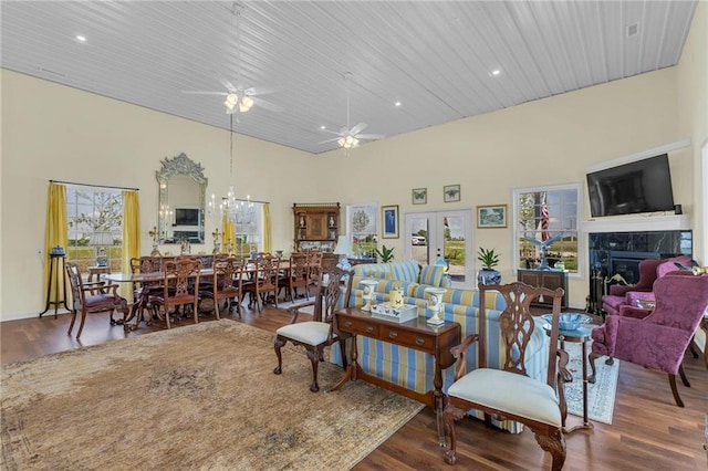 living area featuring a towering ceiling, plenty of natural light, wood finished floors, a premium fireplace, and a ceiling fan