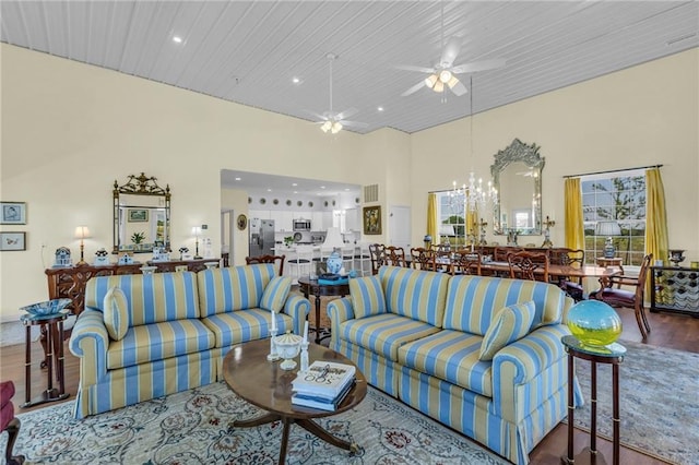 living area featuring a chandelier, recessed lighting, wood finished floors, ceiling fan, and a towering ceiling
