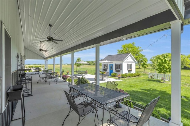 view of patio featuring outdoor dining space, a ceiling fan, and an outbuilding