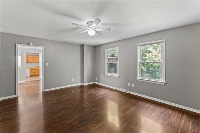 empty room featuring ceiling fan, dark wood-style floors, a textured ceiling, and baseboards