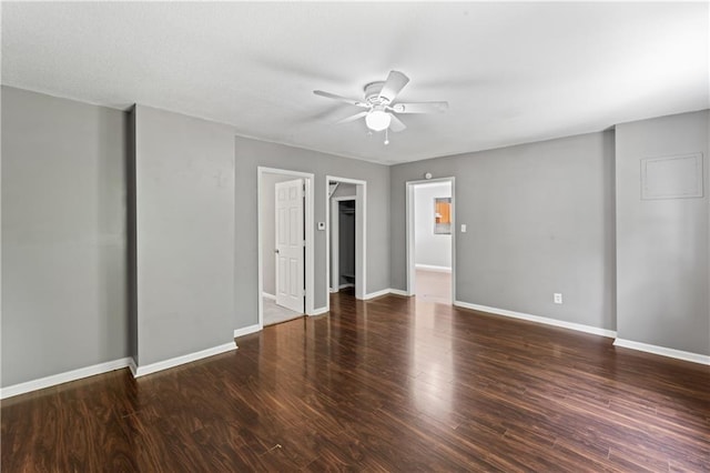 unfurnished bedroom featuring baseboards, wood finished floors, a walk in closet, a closet, and ceiling fan