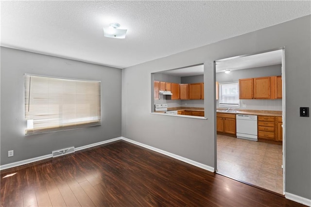 unfurnished living room with dark wood-style floors, baseboards, and a textured ceiling