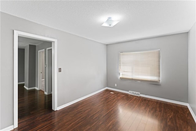spare room with wood finished floors, baseboards, and a textured ceiling