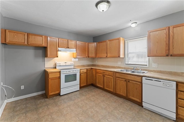 kitchen featuring white appliances, a sink, under cabinet range hood, light countertops, and baseboards