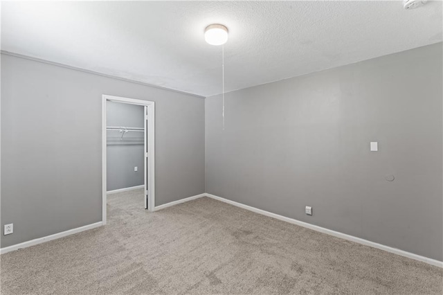 unfurnished bedroom featuring carpet, a spacious closet, baseboards, a closet, and a textured ceiling