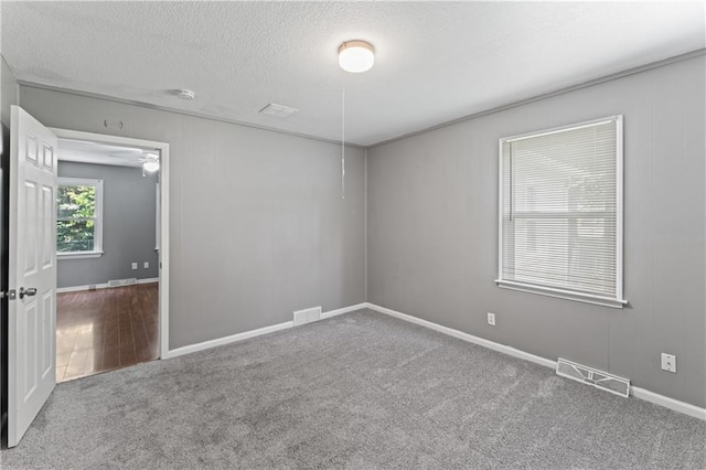 carpeted spare room featuring a textured ceiling and baseboards
