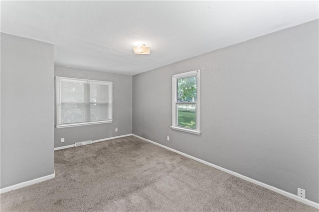 carpeted empty room featuring baseboards