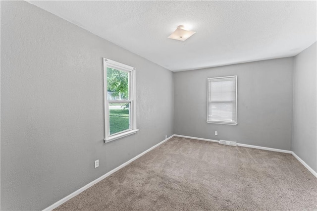 unfurnished room with carpet floors, baseboards, and a textured ceiling