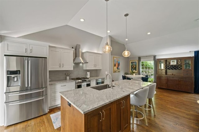 10319 W 92nd Pl, Overland Park, KS 66214 - kitchen featuring stainless steel appliances, wall chimney range hood, lofted ceiling, white cabinets, and tasteful backsplash