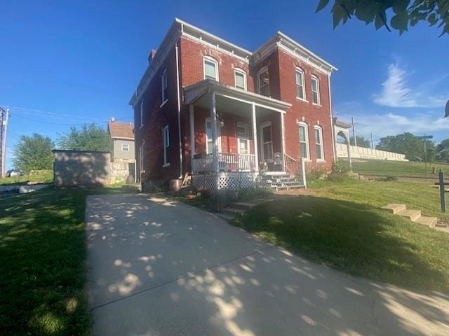 432 S 5th St, Atchison, KS 66002 - view of front of home with a porch, a front lawn, and brick siding