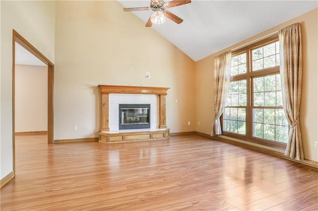 6503 NW Sioux Ct, Parkville, MO 64152 - unfurnished living room featuring light wood-style floors, high vaulted ceiling, a ceiling fan, baseboards, and a tiled fireplace
