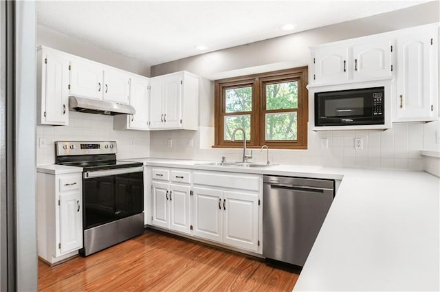 6503 NW Sioux Ct, Parkville, MO 64152 - kitchen featuring stainless steel appliances, under cabinet range hood, a sink, light countertops, and white cabinets