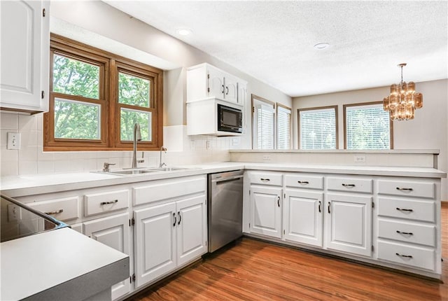 6503 NW Sioux Ct, Parkville, MO 64152 - kitchen with stainless steel dishwasher, a sink, a peninsula, a textured ceiling, and white cabinets
