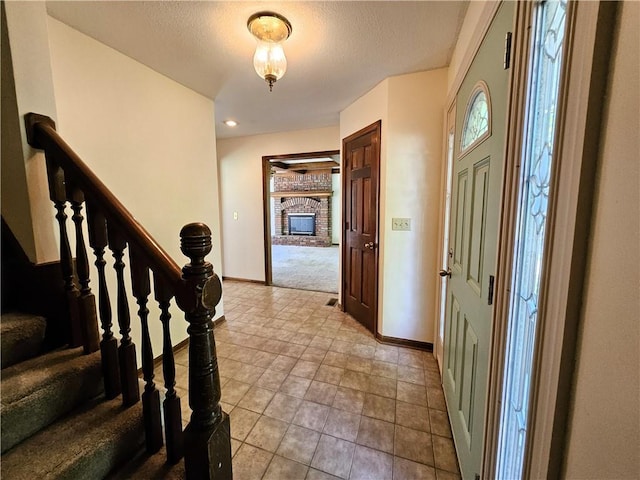 5806 N Kensington Ave, Kansas City, MO 64119 - entryway with baseboards, stairway, carpet flooring, a fireplace, and a textured ceiling