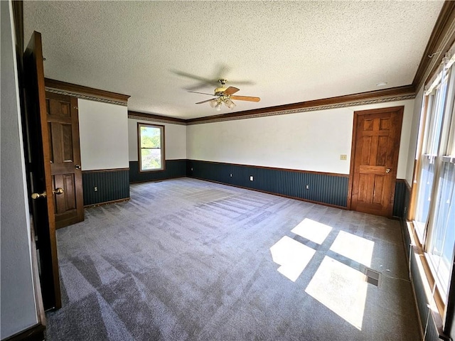 5806 N Kensington Ave, Kansas City, MO 64119 - unfurnished bedroom featuring a wainscoted wall, a textured ceiling, crown molding, carpet flooring, and a ceiling fan