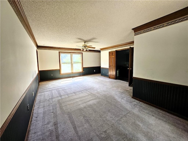 5806 N Kensington Ave, Kansas City, MO 64119 - spare room with crown molding, a textured ceiling, ceiling fan, a wainscoted wall, and carpet