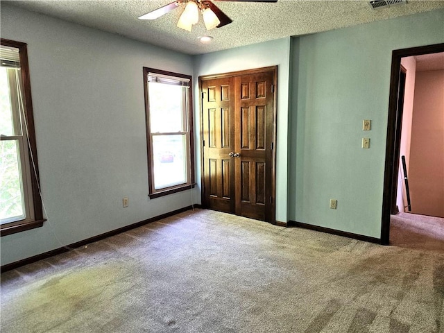 5806 N Kensington Ave, Kansas City, MO 64119 - unfurnished bedroom with carpet floors, multiple windows, a textured ceiling, baseboards, and a closet