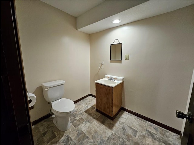 5806 N Kensington Ave, Kansas City, MO 64119 - bathroom featuring baseboards, toilet, stone finish floors, vanity, and recessed lighting