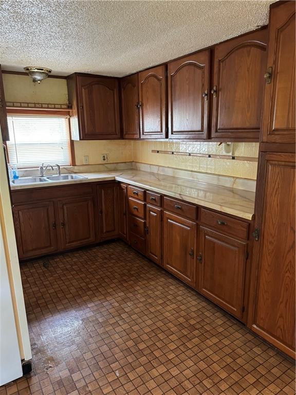 32572 Magnolia Ln, Excelsior Springs, MO 64024 - kitchen with a sink, light countertops, a textured ceiling, freestanding refrigerator, and tasteful backsplash