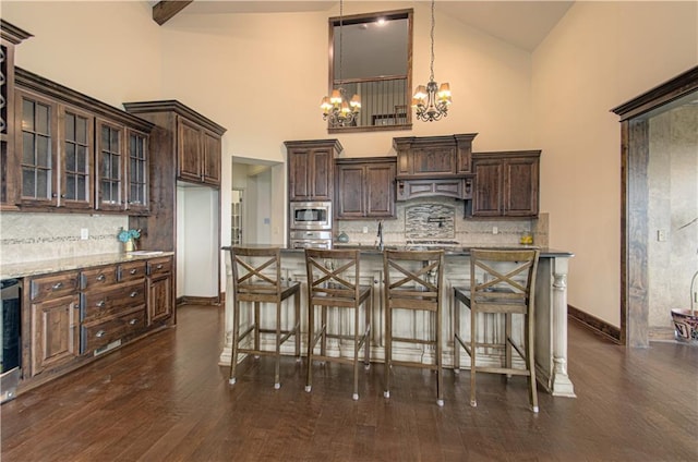 1110 Metfield Ln, Raymore, MO 64083 - kitchen with appliances with stainless steel finishes, high vaulted ceiling, a chandelier, dark brown cabinets, and backsplash