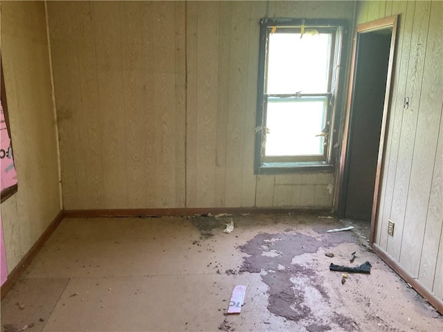 unfurnished room with plenty of natural light and wooden walls